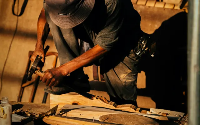 A carpenter working on timber with hand tools in a workshop
