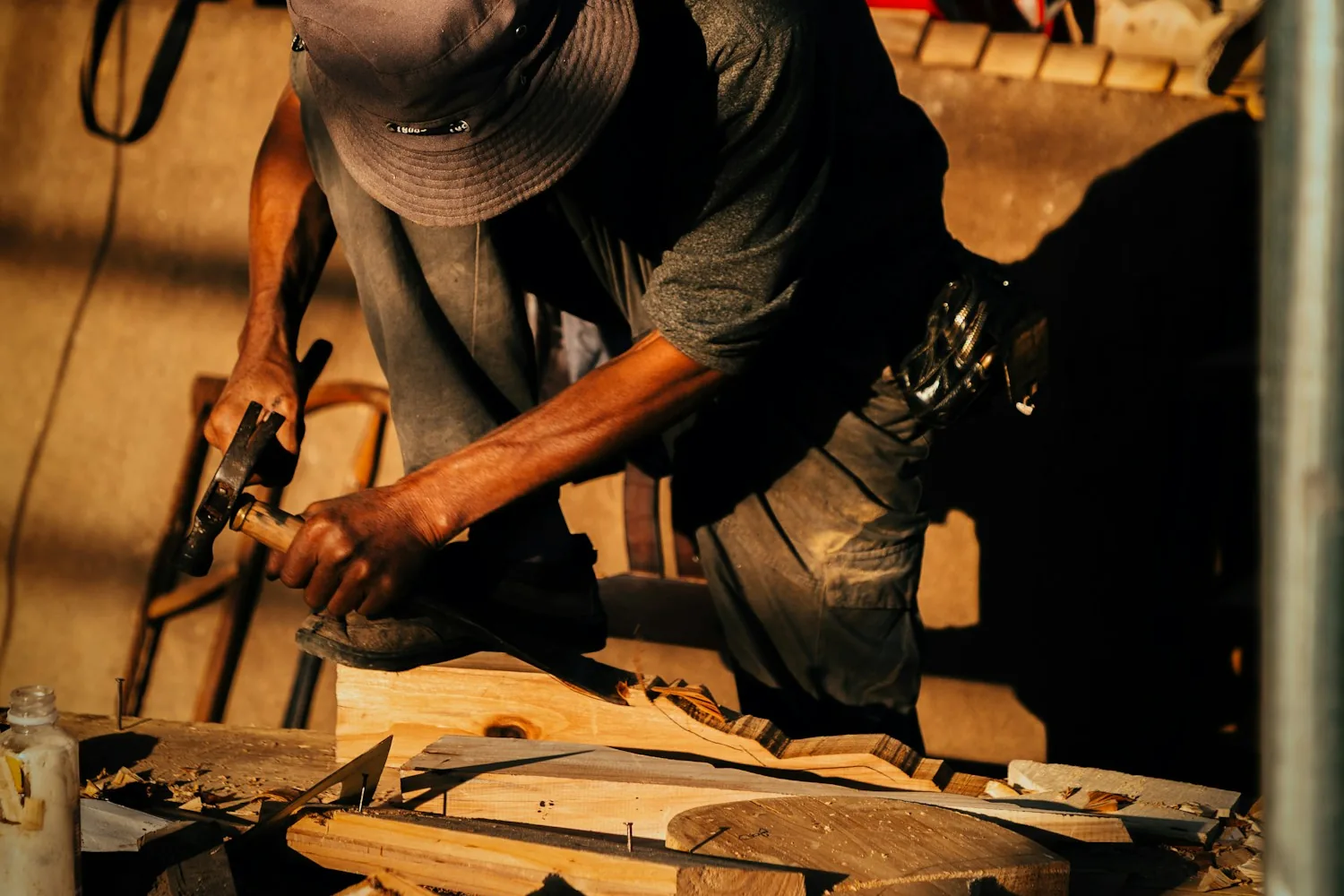 A carpenter working on timber with hand tools in a workshop