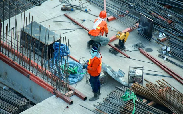 Two construction workers using equipment on a building site