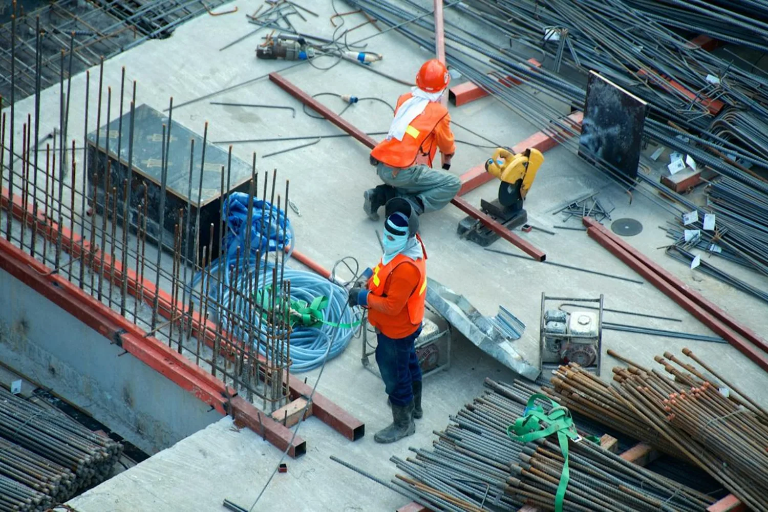 Two construction workers using equipment on a building site