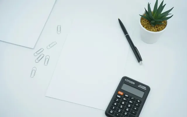 Calculator, pen and paper on a desk