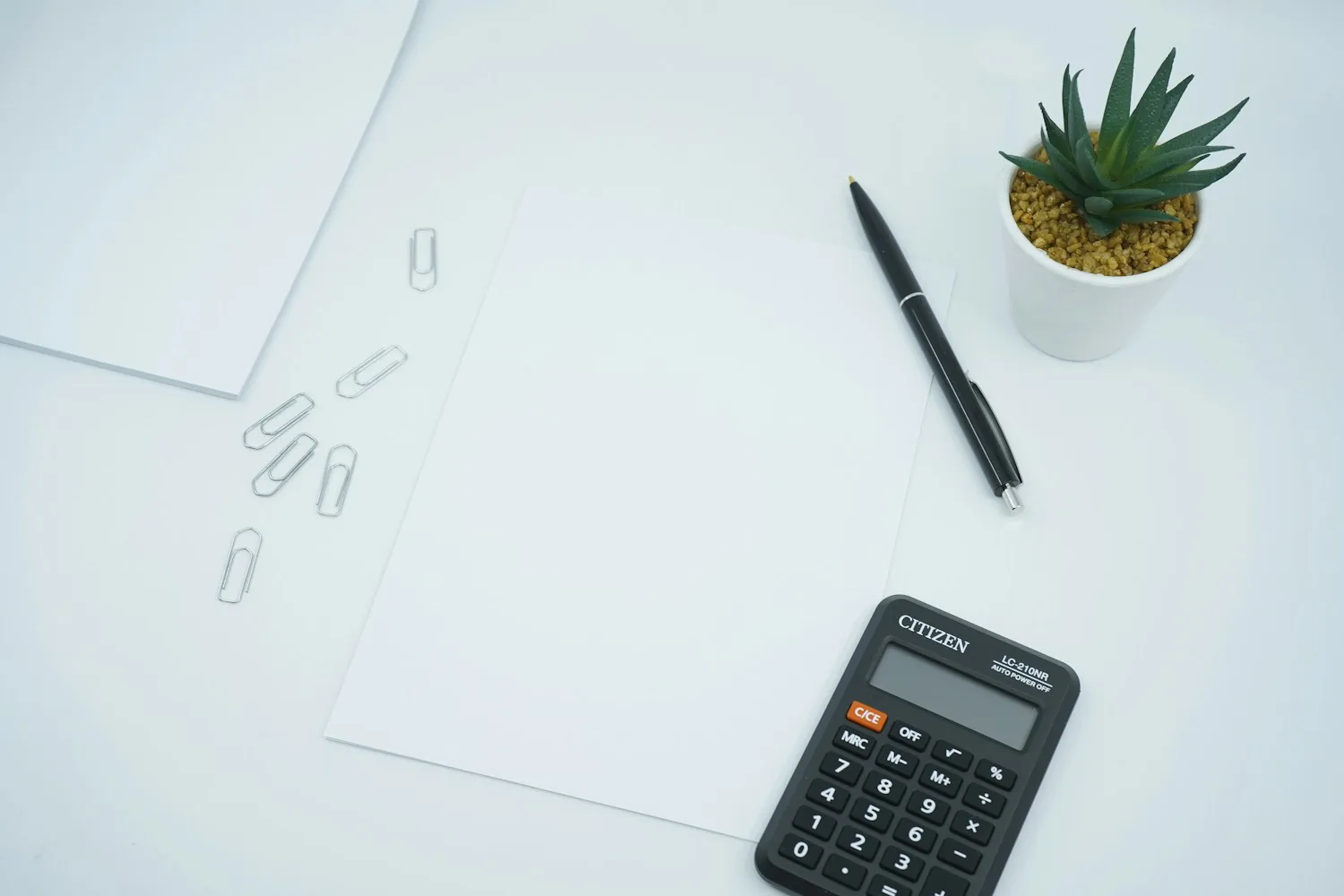 Calculator, pen and paper on a desk